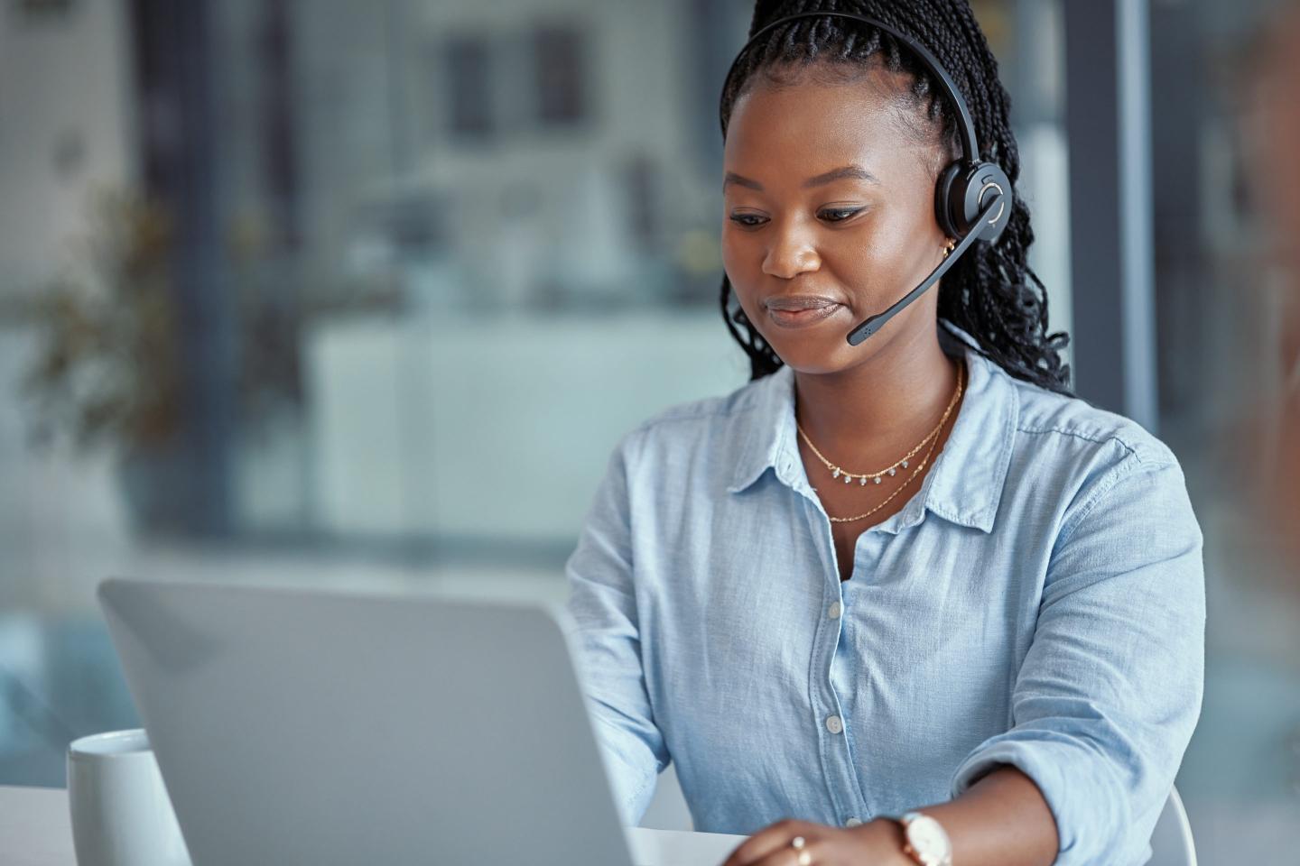 Shot of a young female call center agent using a laptop at work