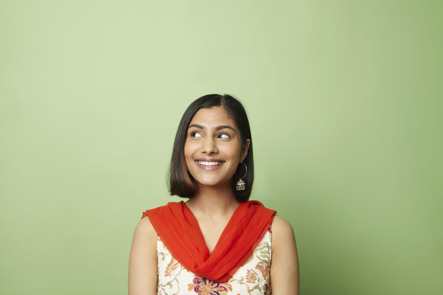 beautiful south asian woman glancing to the side against green background
