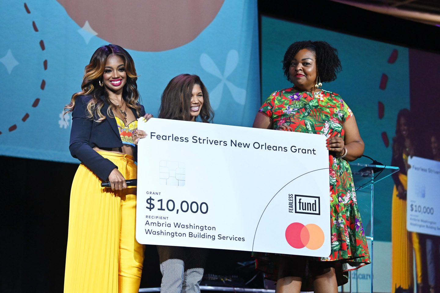 3 women standing onstage holding large check