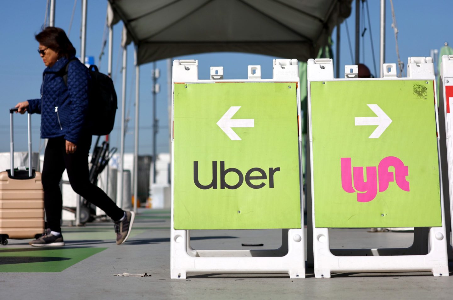 A sign at L.A. airport indicates Uber pickup line to the left and Lyft to the right.