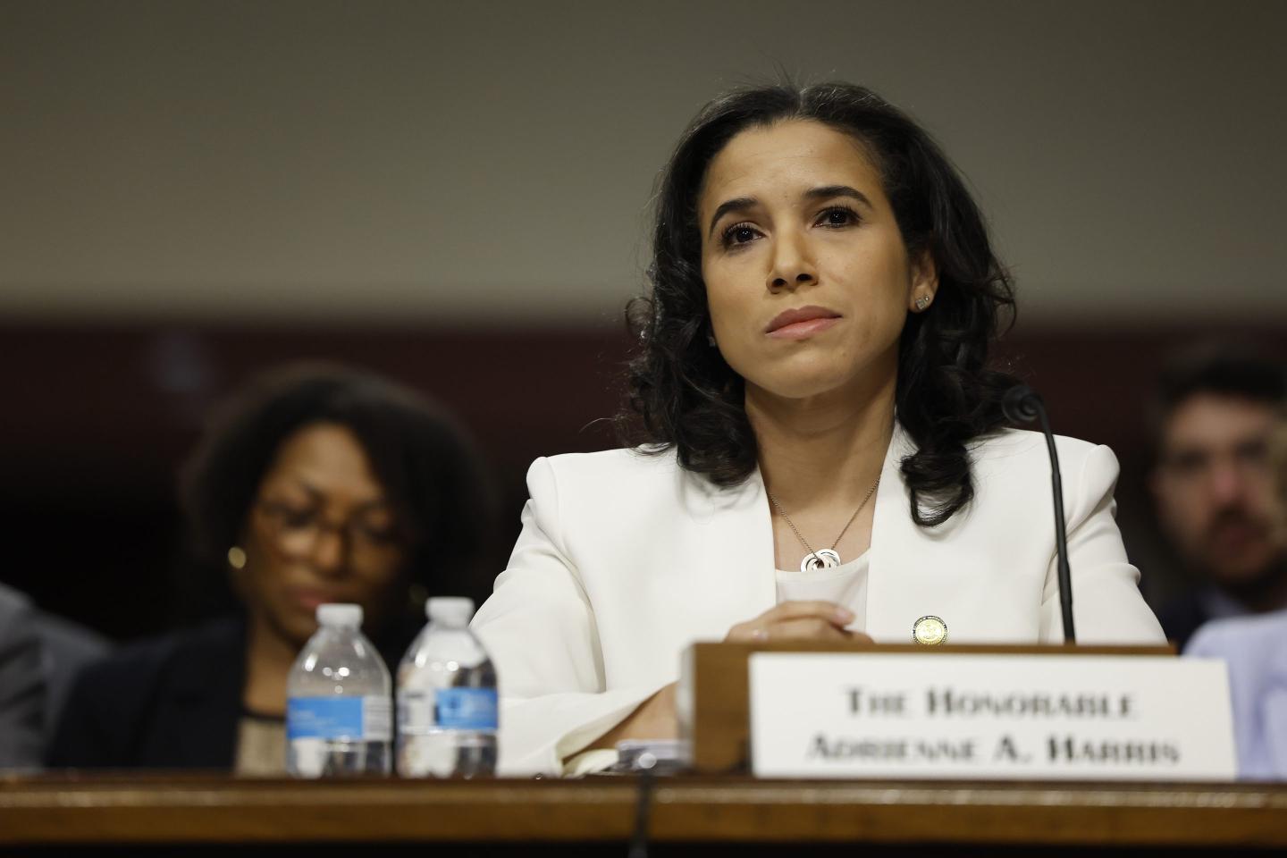 Woman wearing white suit jacket sitting in front of a podium