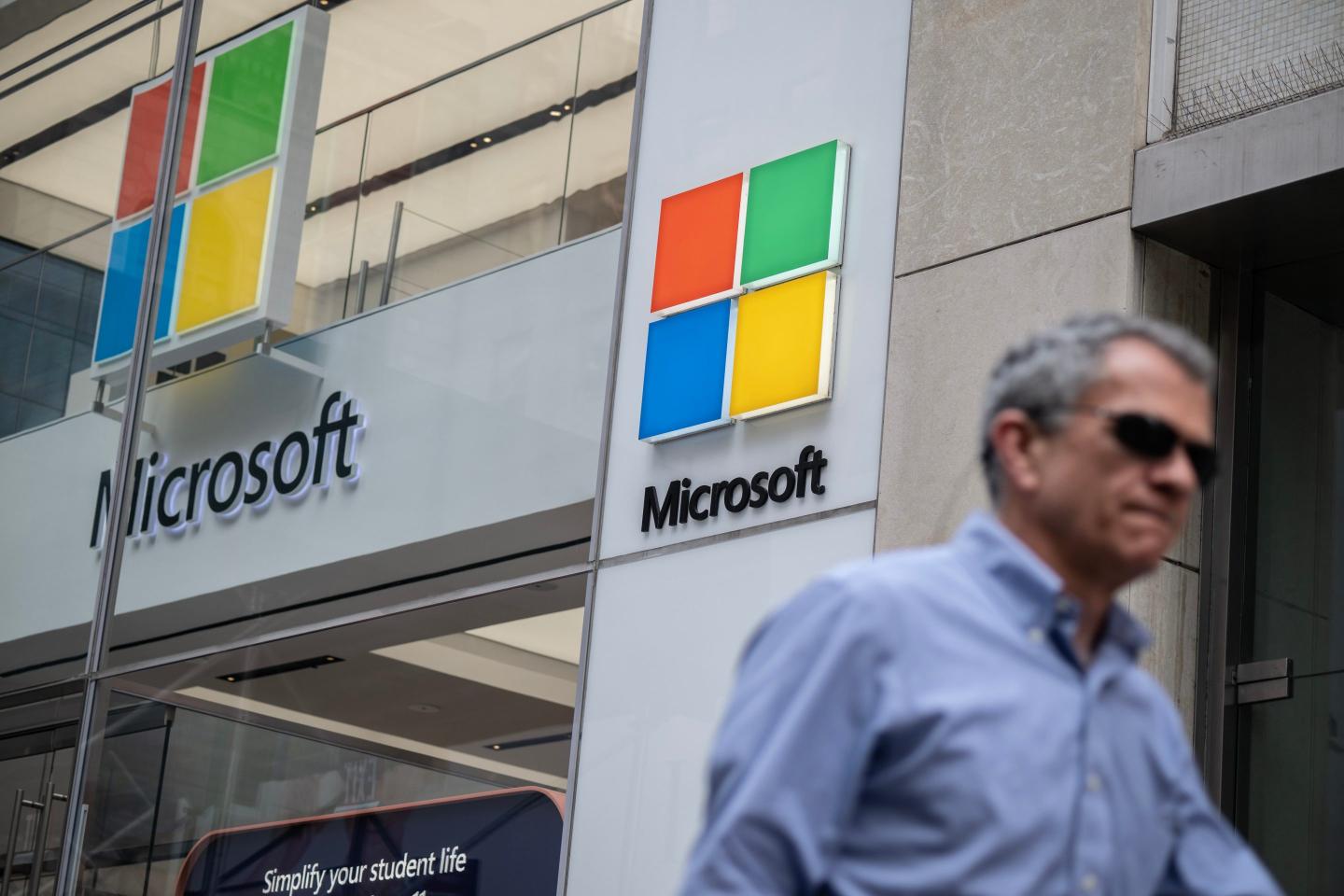 A man passes underneath a Microsoft sign on the street.