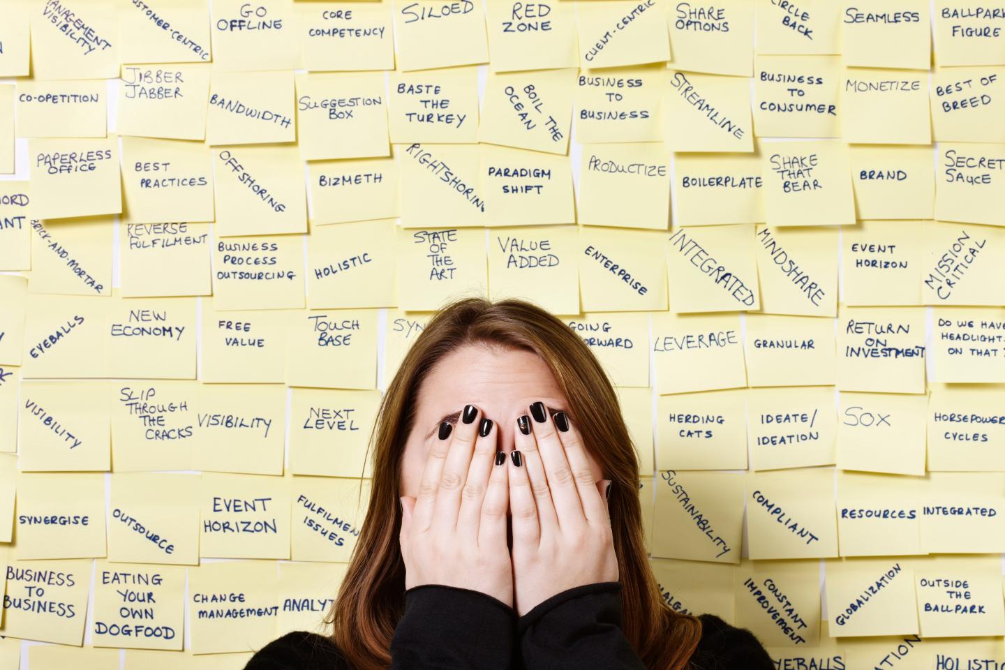 Woman holding her hands over her eyes against a background of cryptic writing on a wall.
