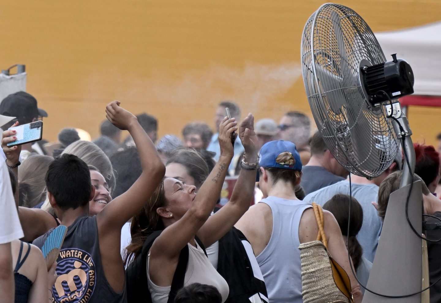 Tourists cool off by a water spraying ventilator before entering the Colosseum monument on July 24, 2023 in Rome during a heatwave.