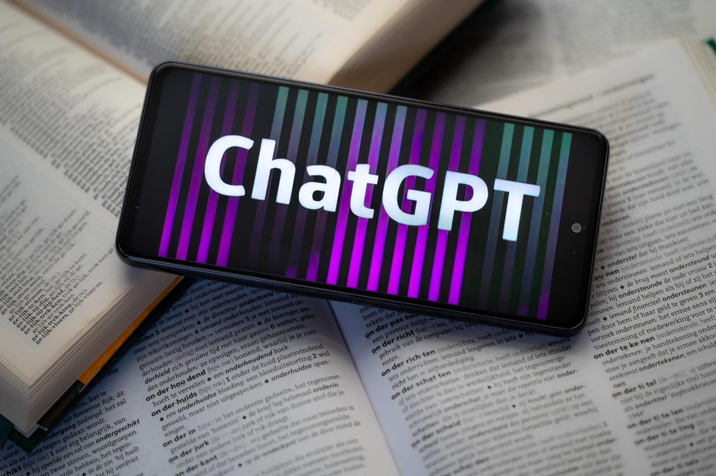 ChatGPT displayed on a smart phone with a dictionary book, seen in this photo illustration.