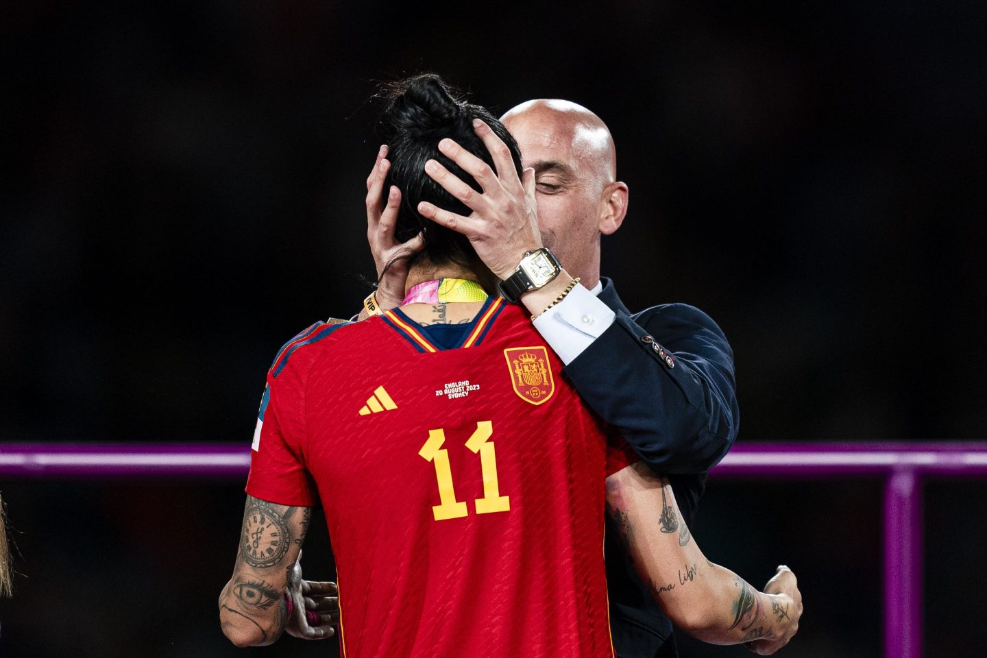 female soccer player being forcibly kissed by a man wearing a suit