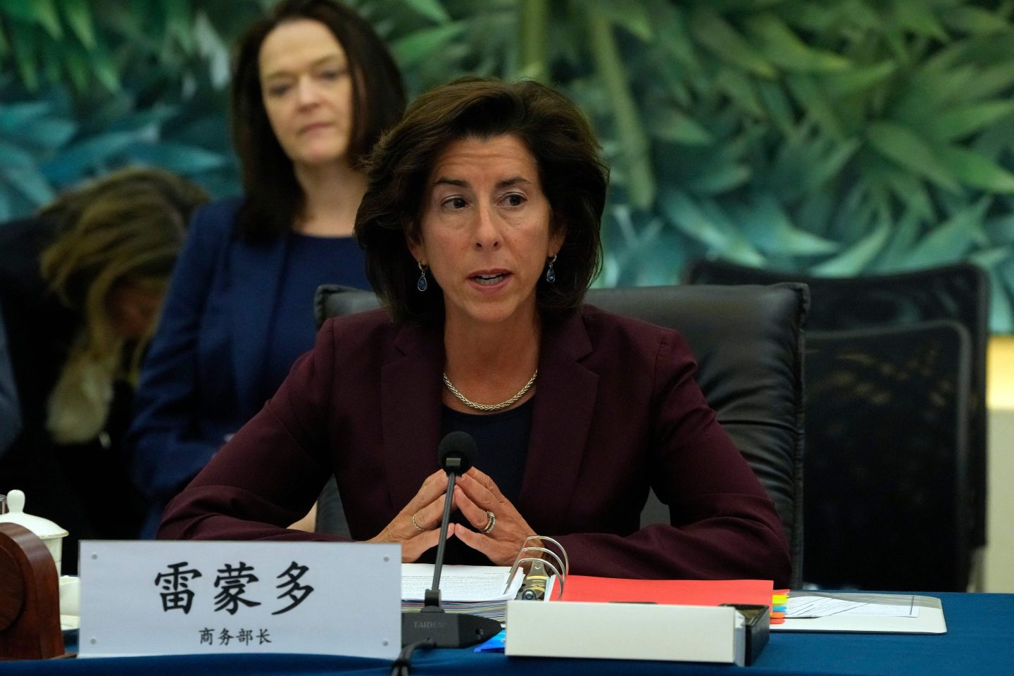 U.S. Commerce Secretary Gina Raimondo sits at a table in front of a nameplate with Chinese lettering.