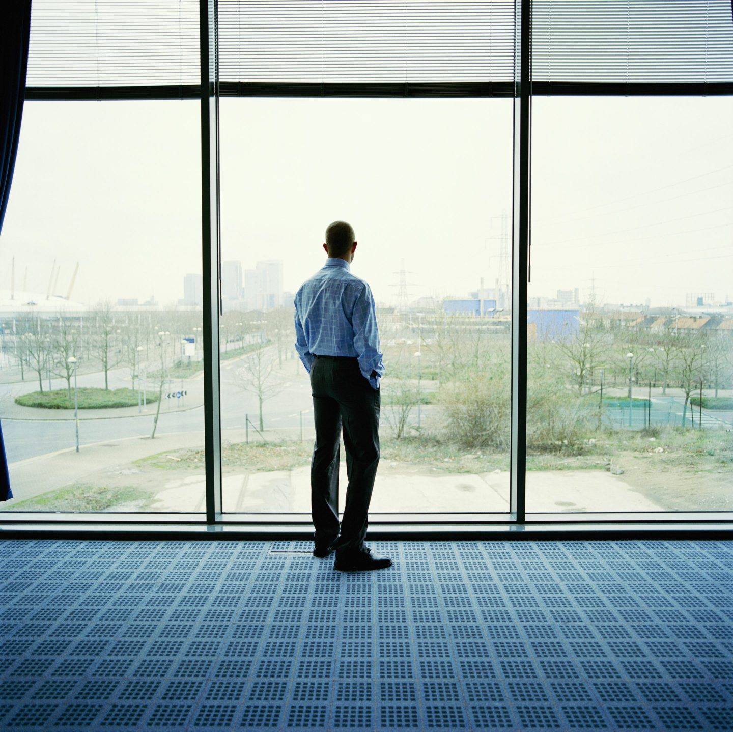 Businessman looking out of office window, rear view