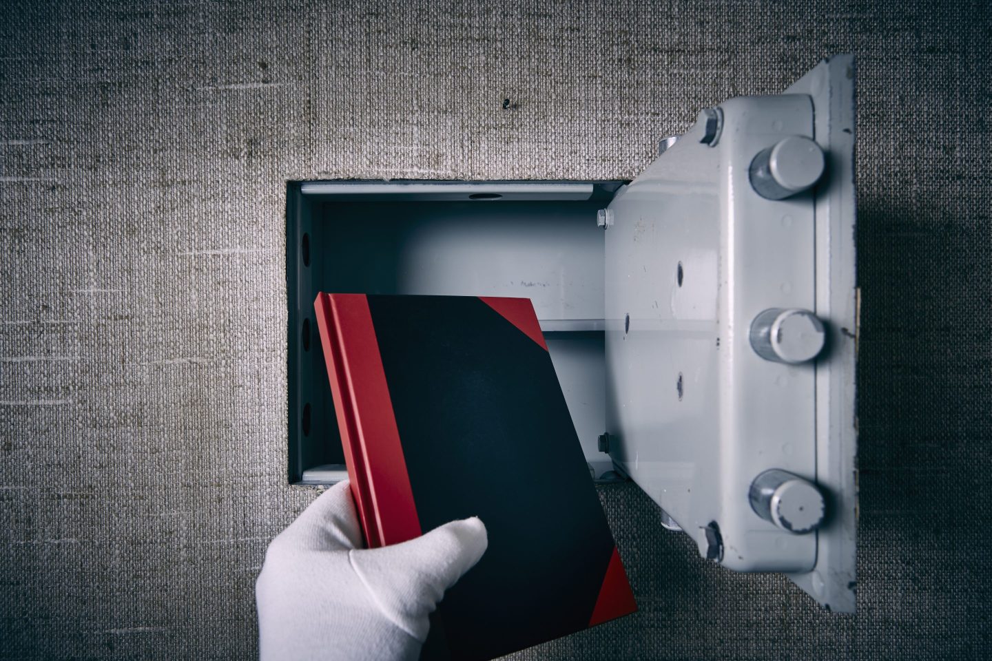 Book being placed into a safe by a gloved hand