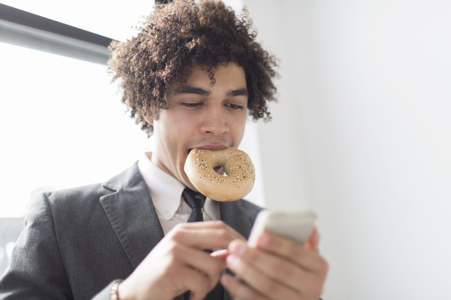 Man eating bagel and working on smartphone