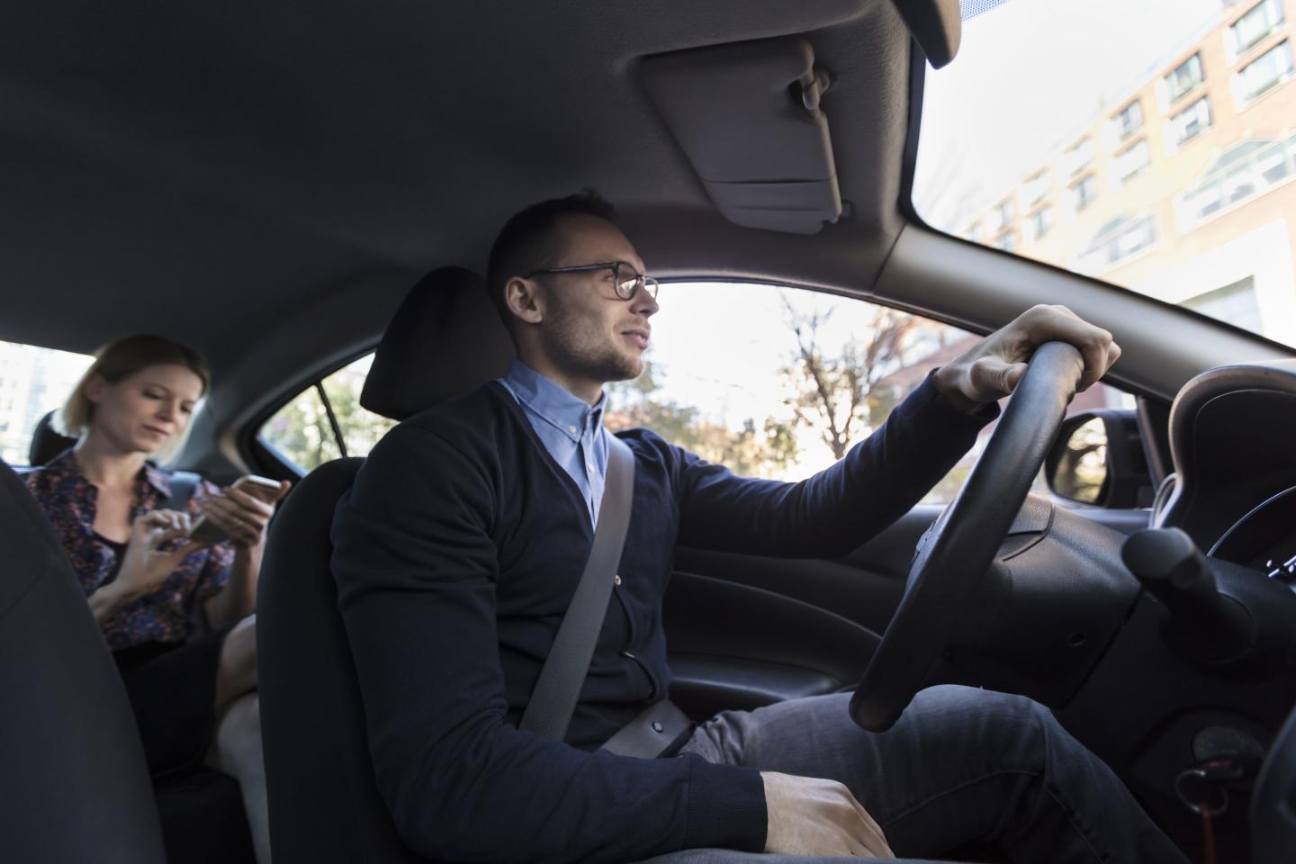 woman in a ride share car being driven by a man.