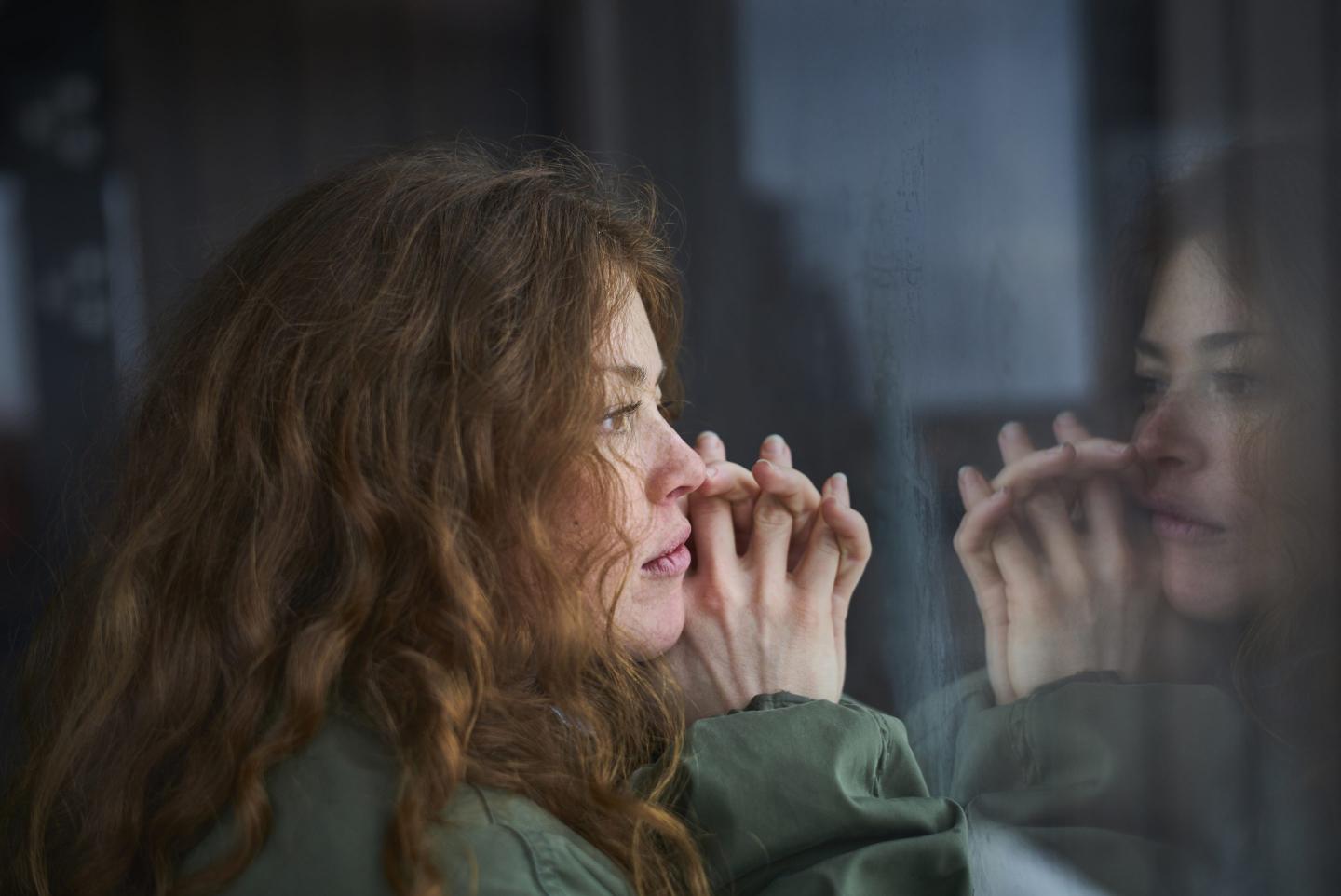 Woman looking out of window into her reflection