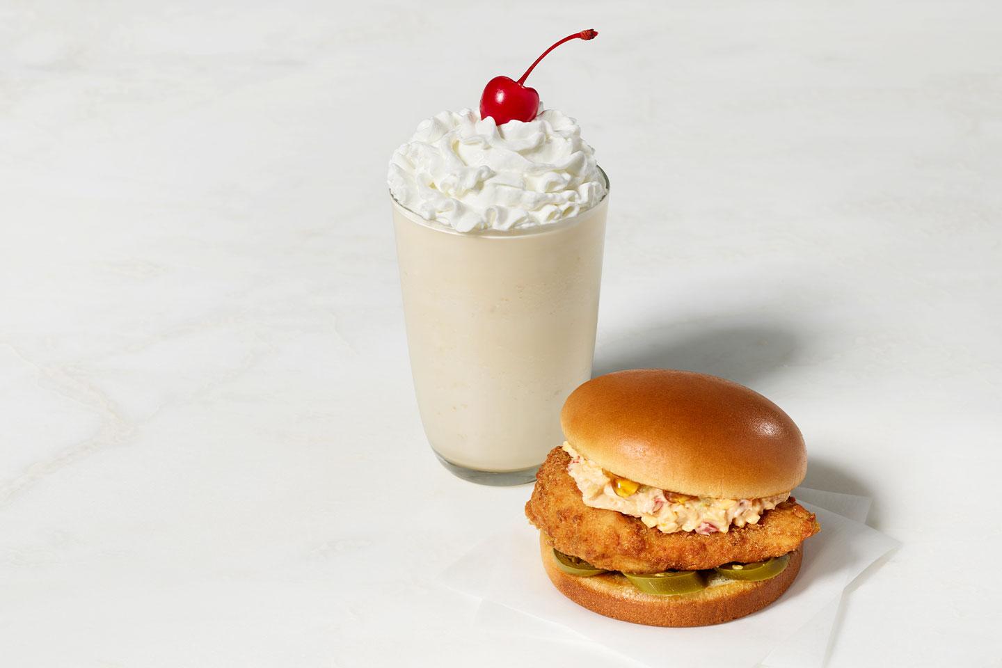 a milk shake and chicken burger on a bun.