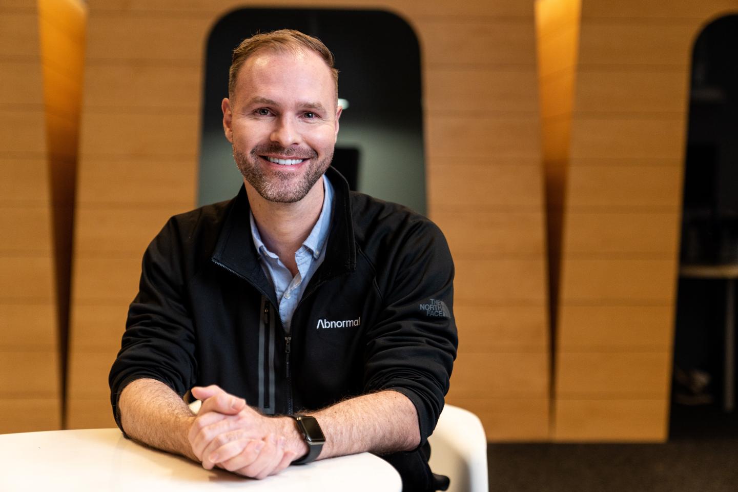 man in fleece jacket smiling with hands folded