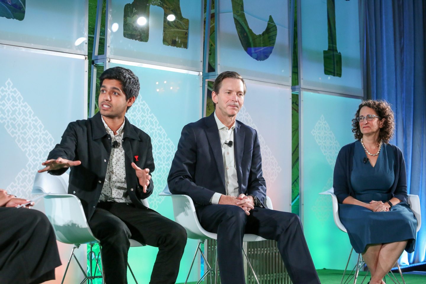 3 people in professional clothing sitting onstage