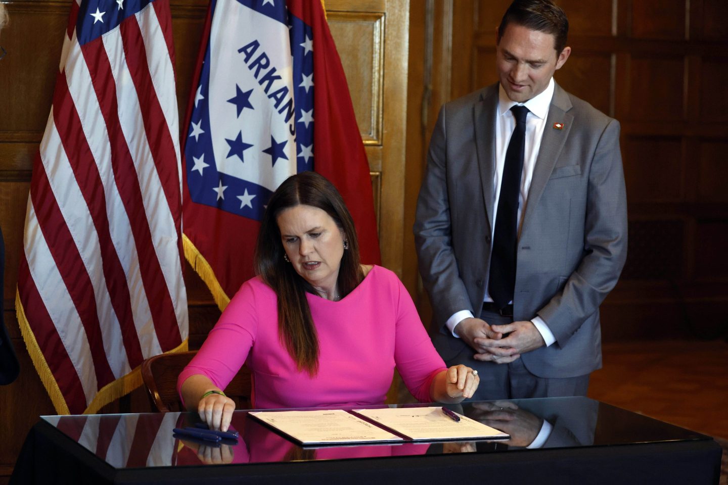 Arkansas Gov. Sarah Huckabee Sanders signs a bill requiring age verification before creating a new social media account as Sen. Tyler Dees, R-Siloam Springs, looks on during a signing ceremony, on April 12, 2023, at the state Capitol in Little Rock.