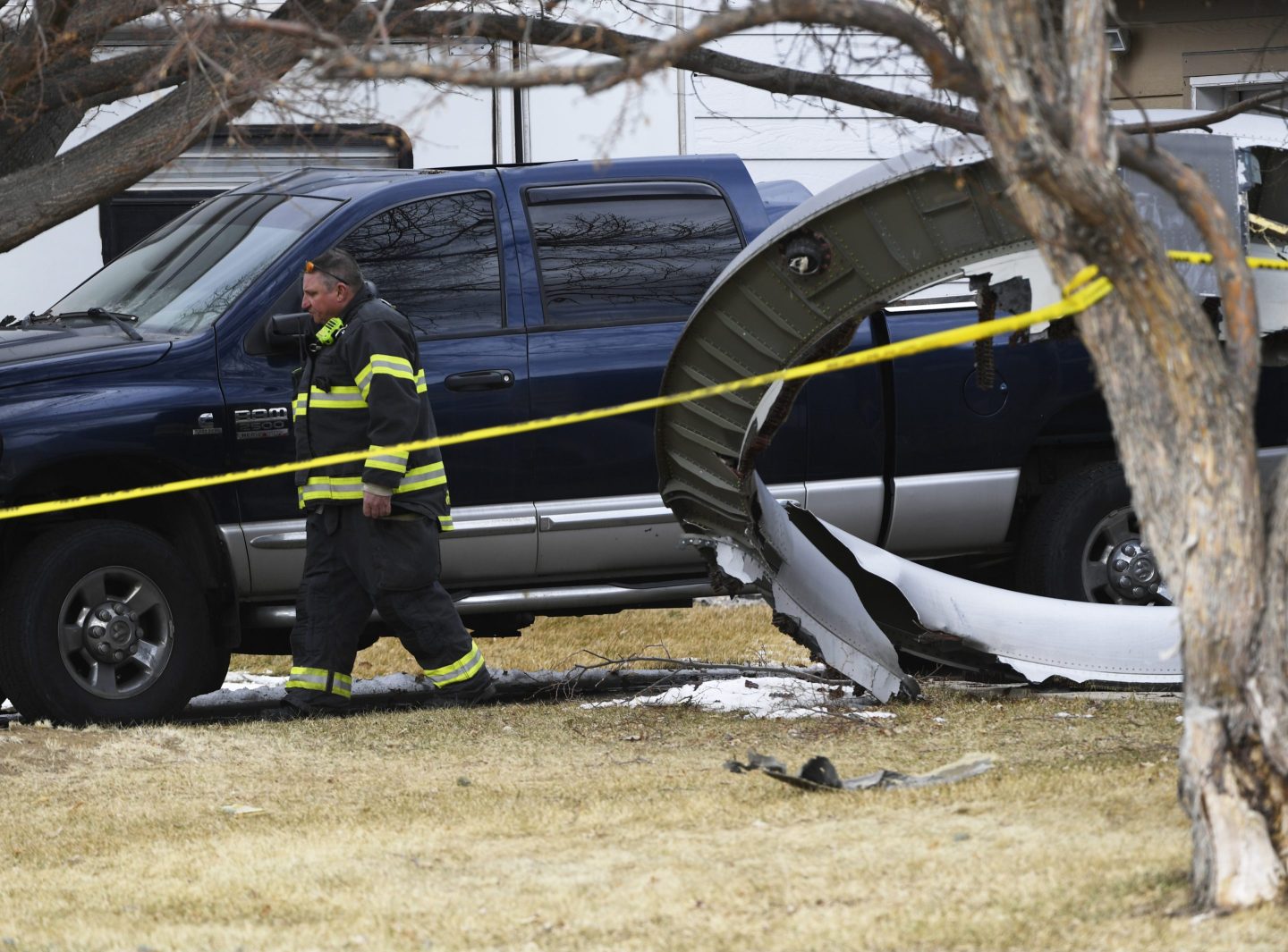 A firefighter walks past a piece of a United airplane engine in a front yard in Broomfield, Colo., on Feb. 20, 2021.