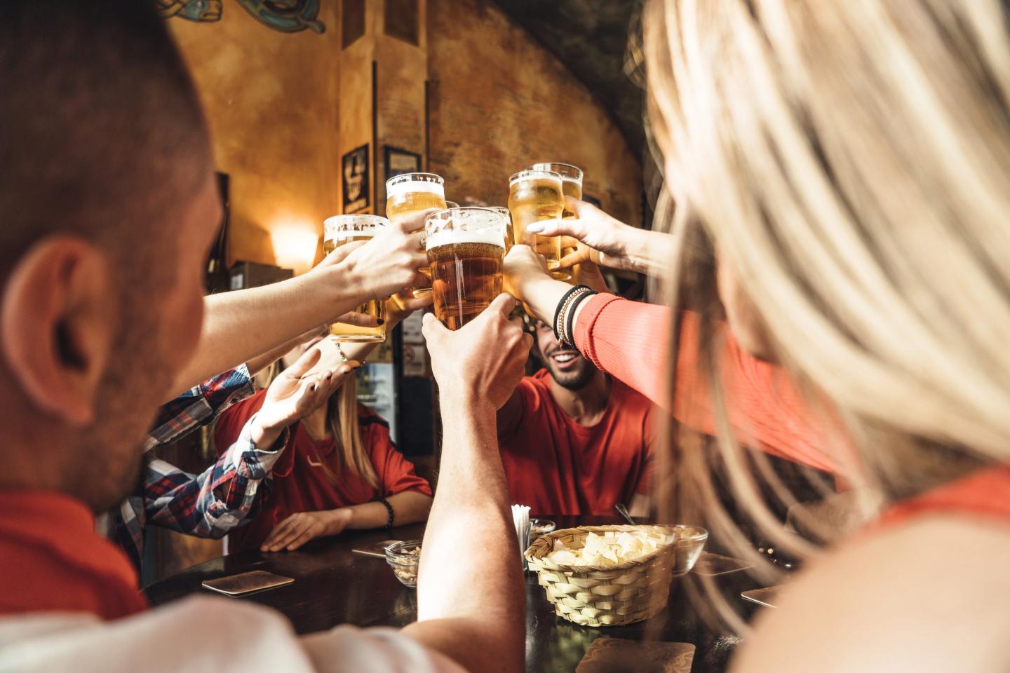 people cheers-ing to pints of beer