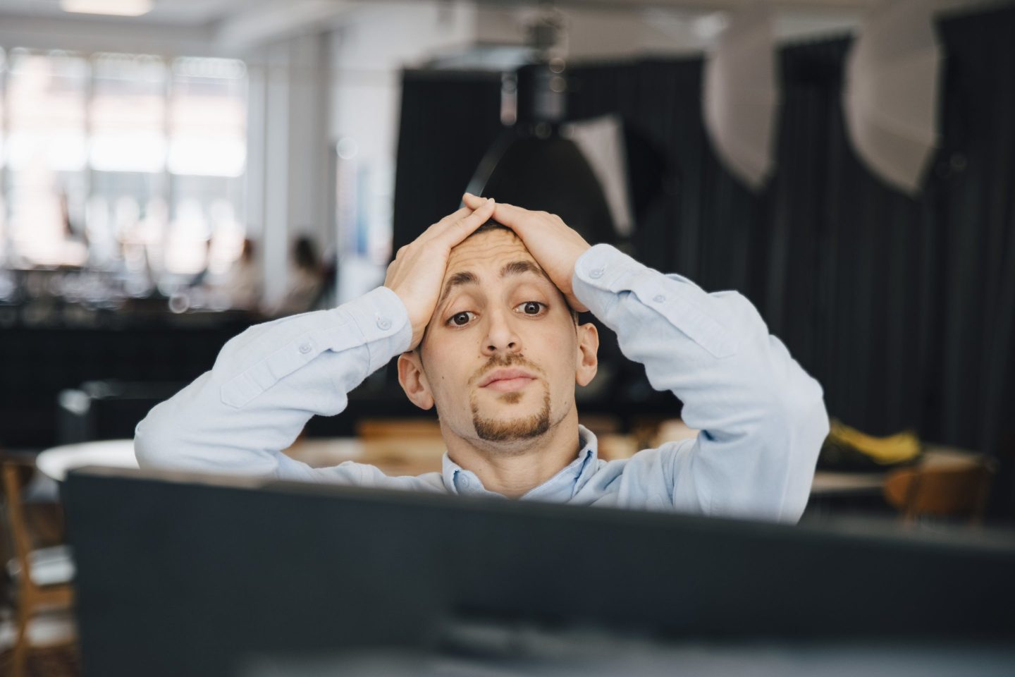 An exhausted computer programmer looking at a monitor