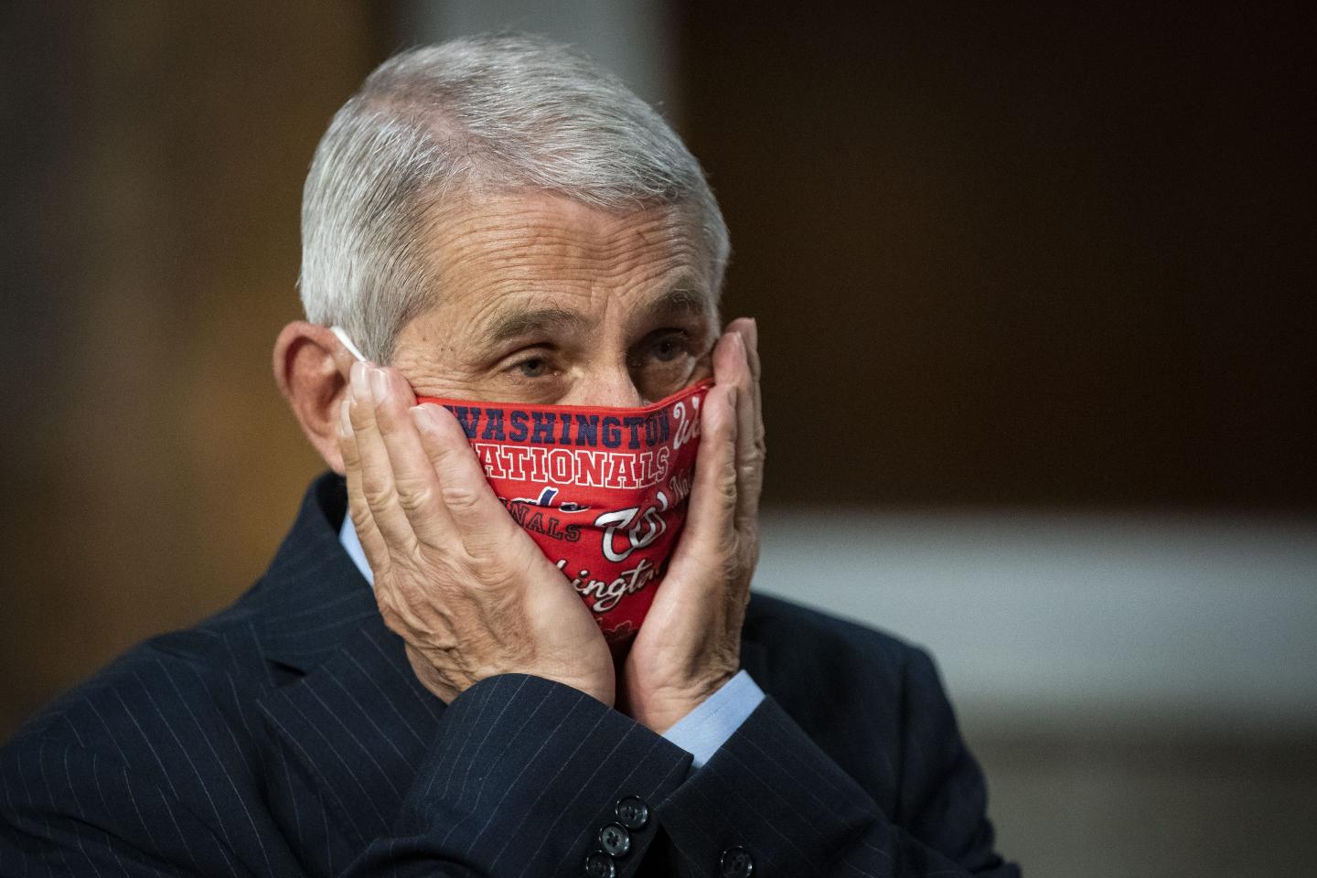 Anthony Fauci adjusts his Washington Nationals face mask