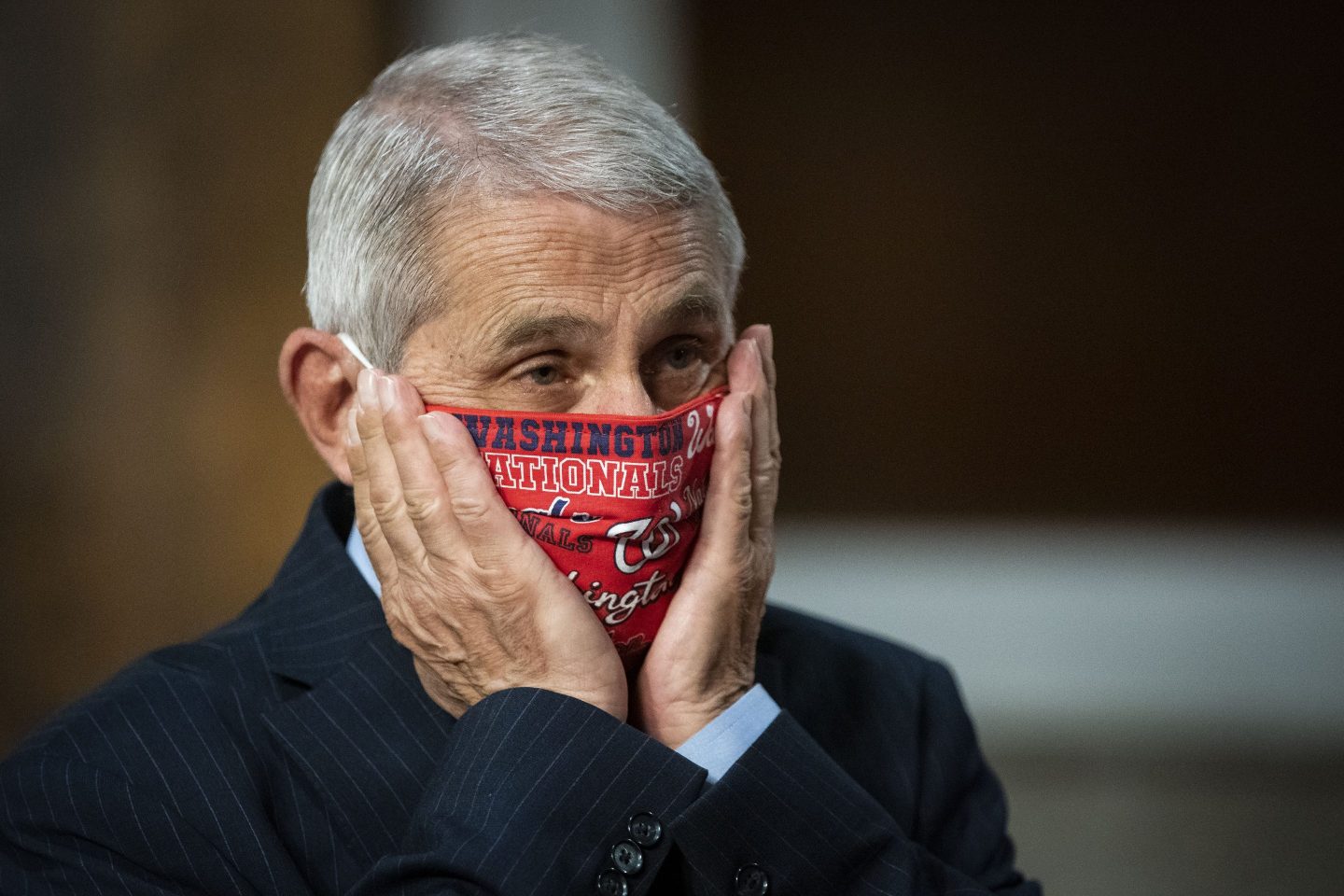 Anthony Fauci adjusts his Washington Nationals face mask