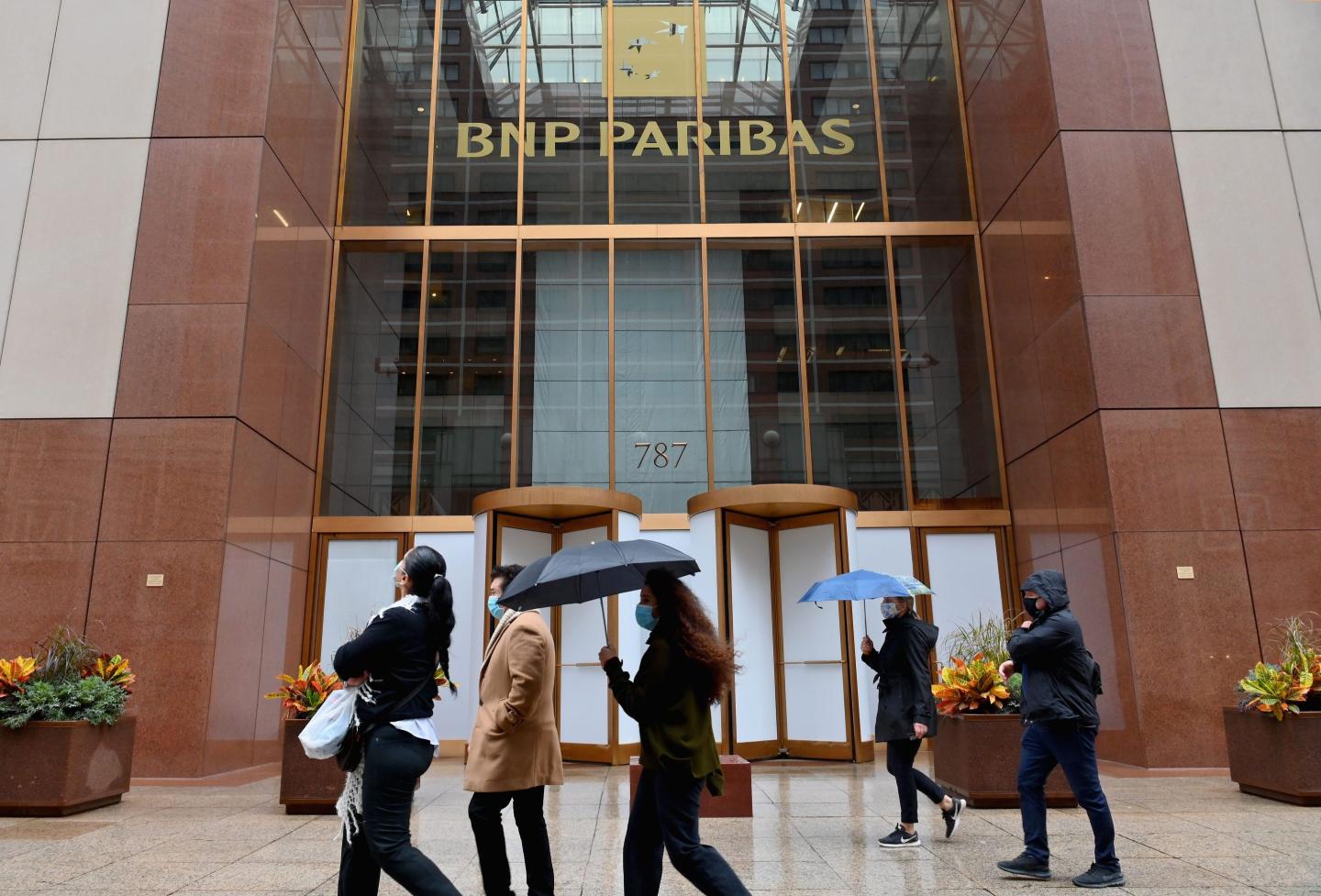 Workers pass outside a BNP Paribas bank