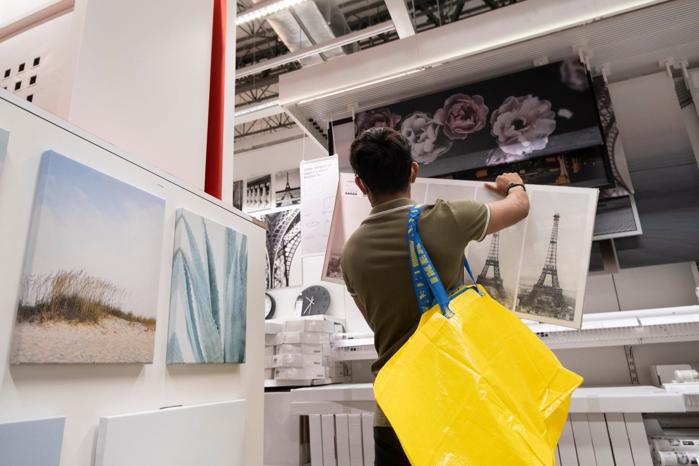 a person with a yellow shopping bag, holding a long painting