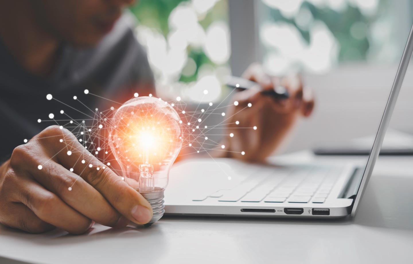 Male hand holding illuminated light bulb