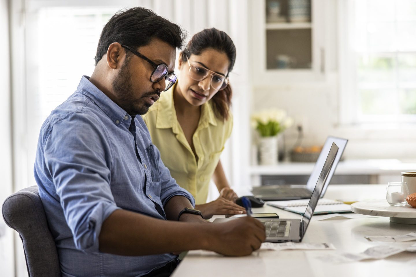 Husband and wife using laptop computers in kitchen