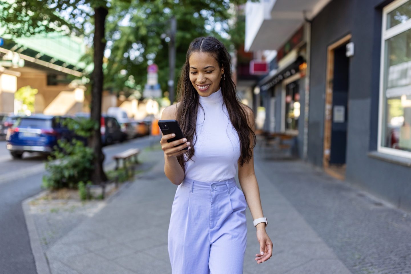 Young smartly dressed woman walking with phone in hand