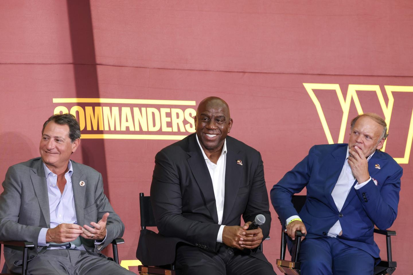 3 men in suits sitting onstage