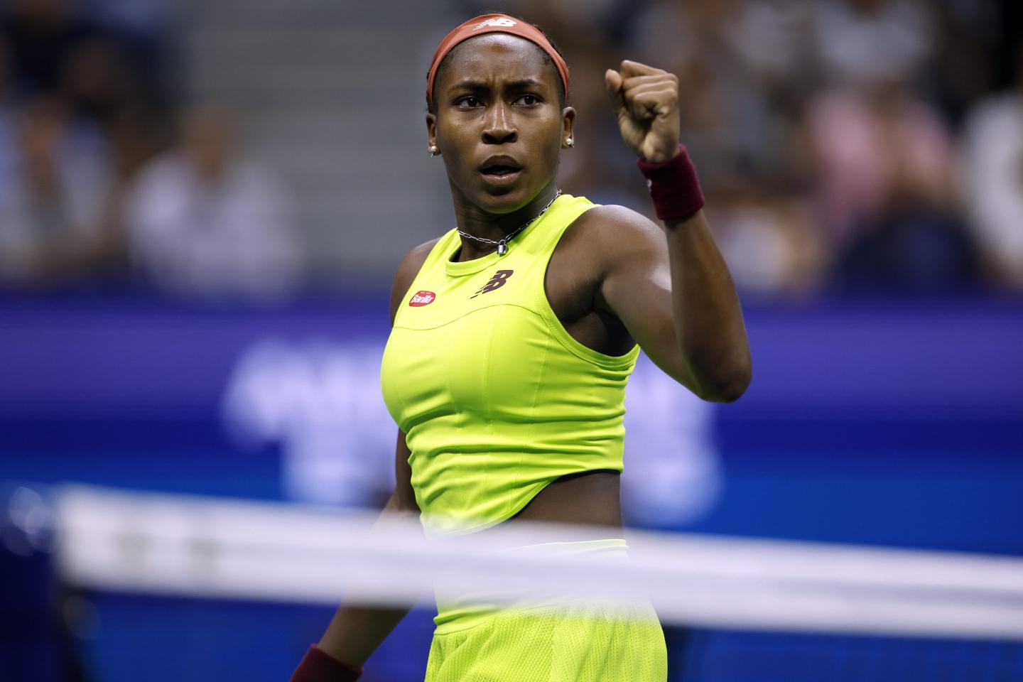 Coco Gauff on the court at the U.S. open, wearing a neon yellow New Balance tank top and skirt.