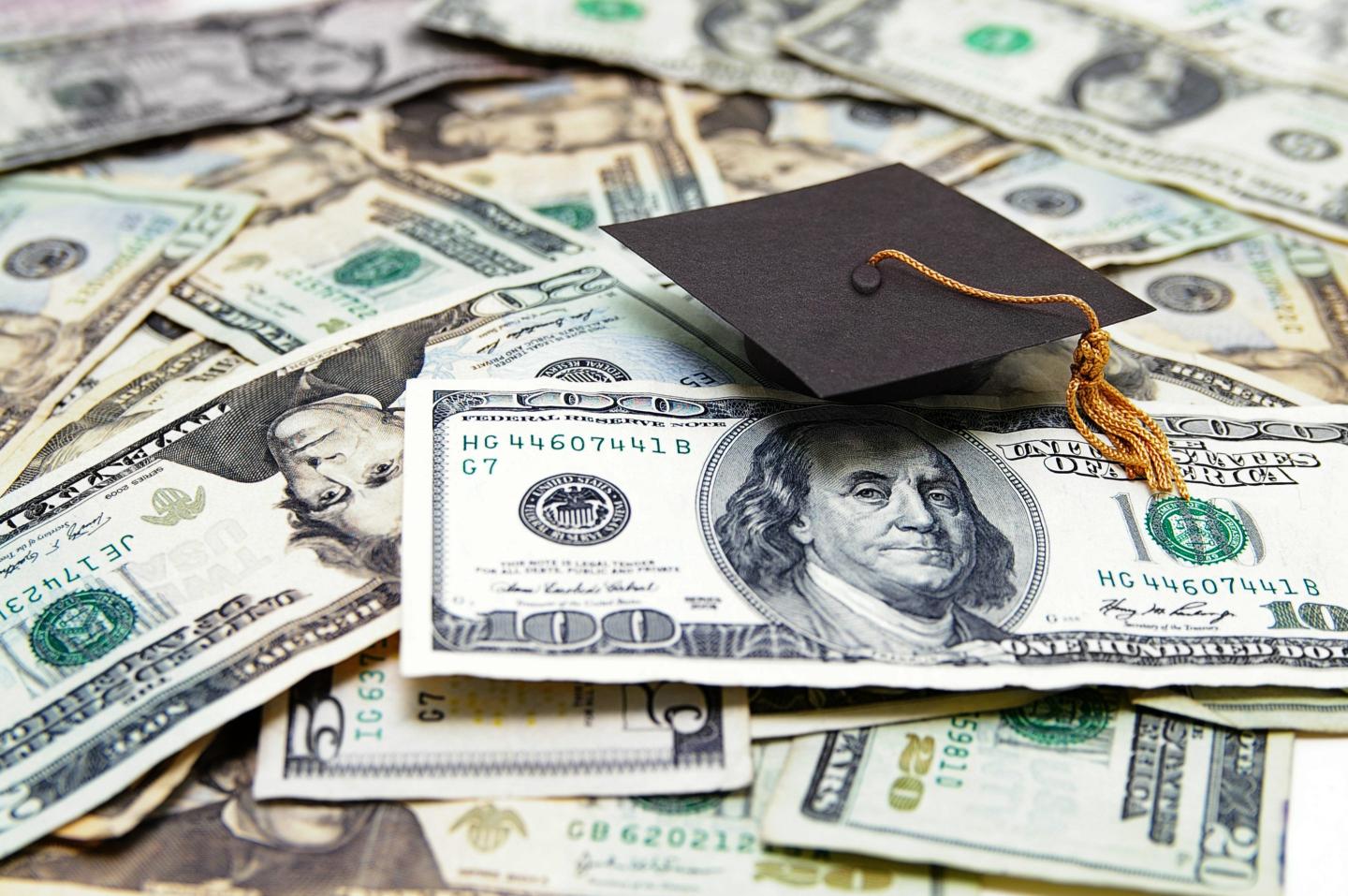 A mini graduation cap sitting on dollar bills