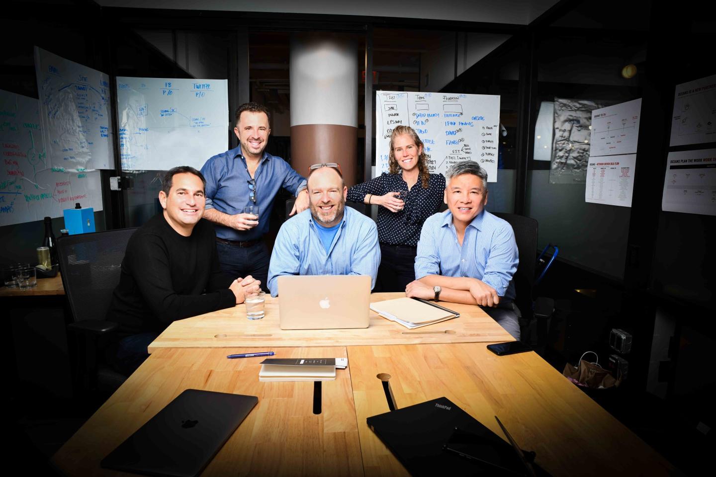 professionals sitting at a desk pose for a photo