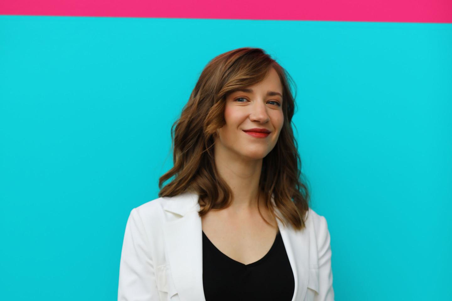 Cassie Kozyrkov stands in front of a blue and pink wall.