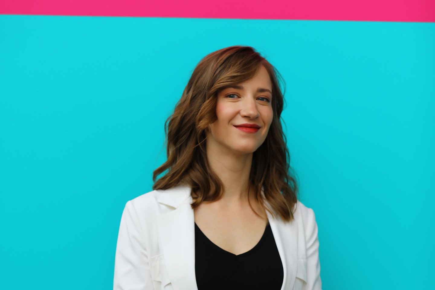 Cassie Kozyrkov stands in front of a blue and pink wall.
