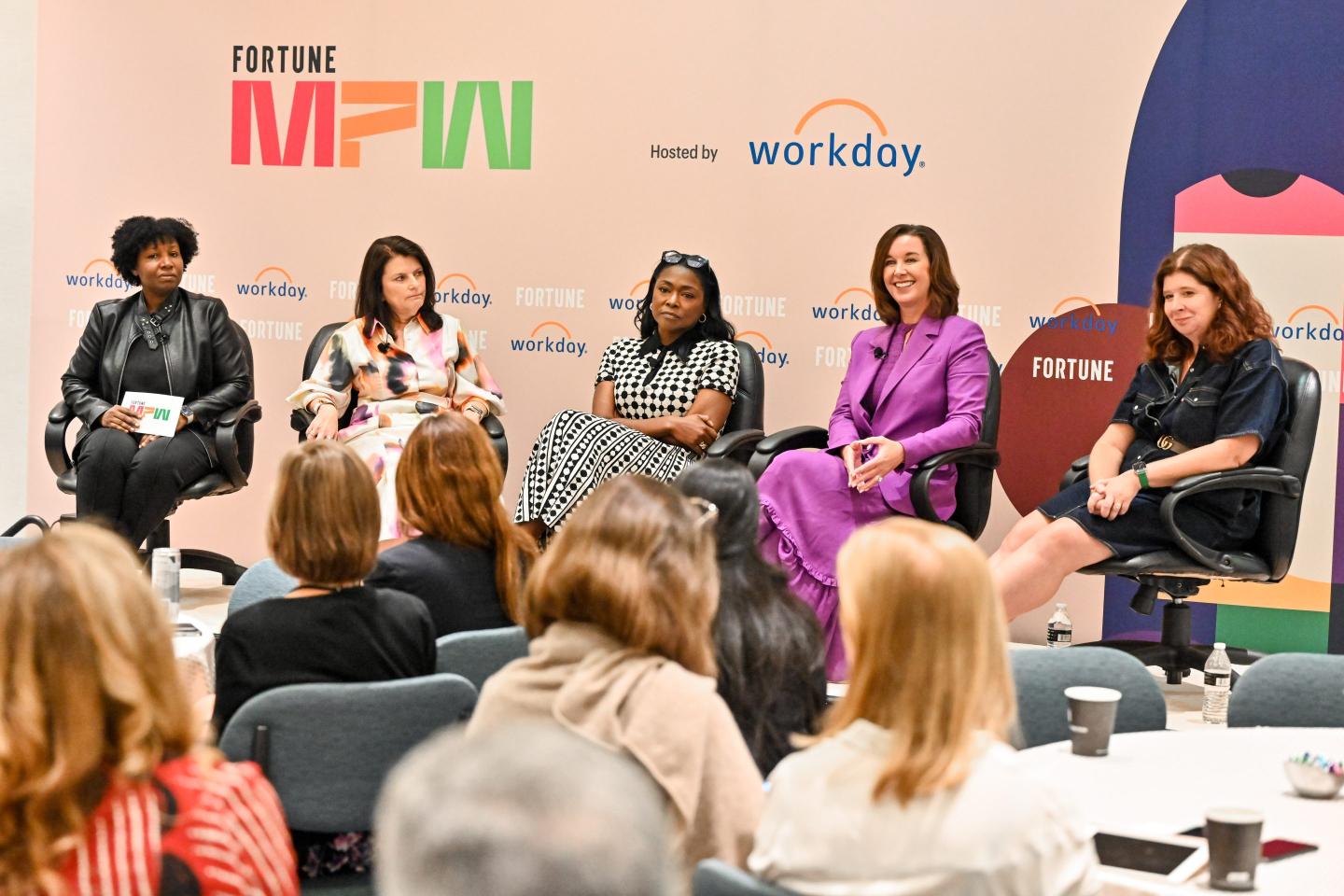 5 businesswomen sitting onstage