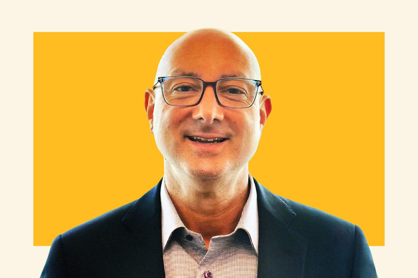man in suit jacket and glasses smiling at camera