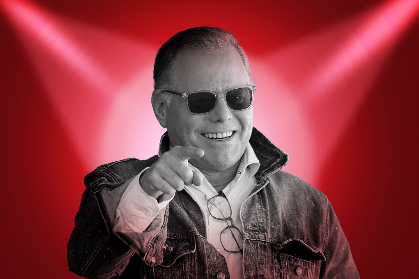 Photo of David Zaslav over a red background with two spotlights coming from the top corners shining onto him.