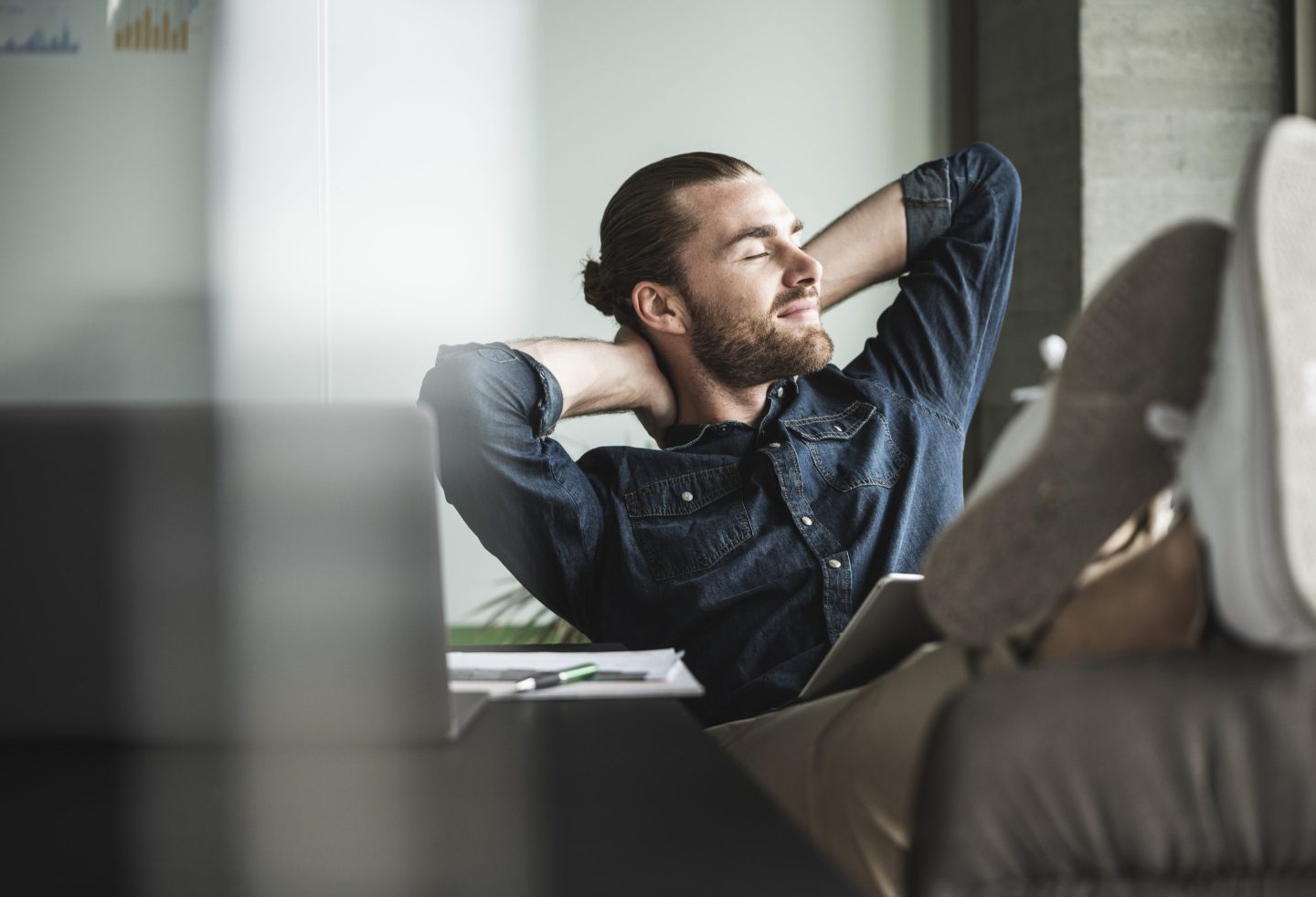 Young man has his feet up on a desk and his eyes closed
