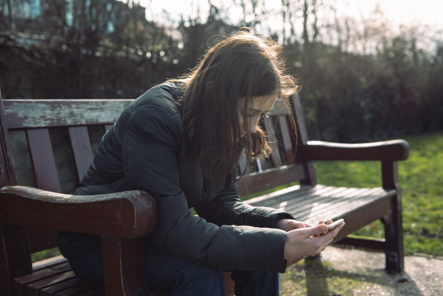 Teenage girl on her phone in the park