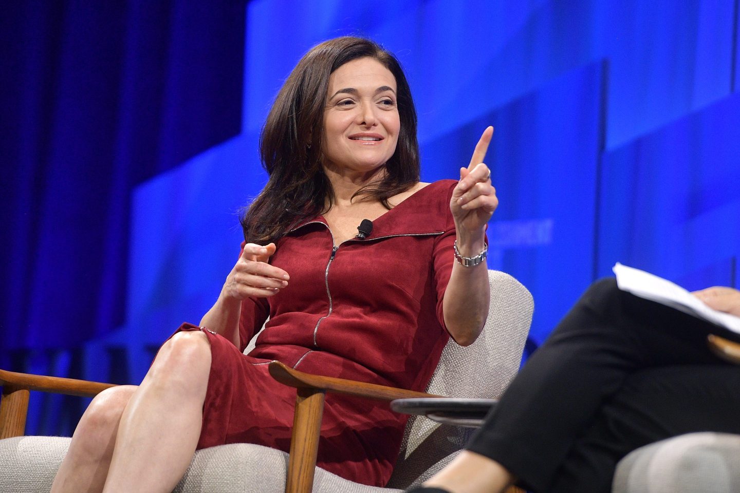 businesswoman in red dress sitting and speaking onstage