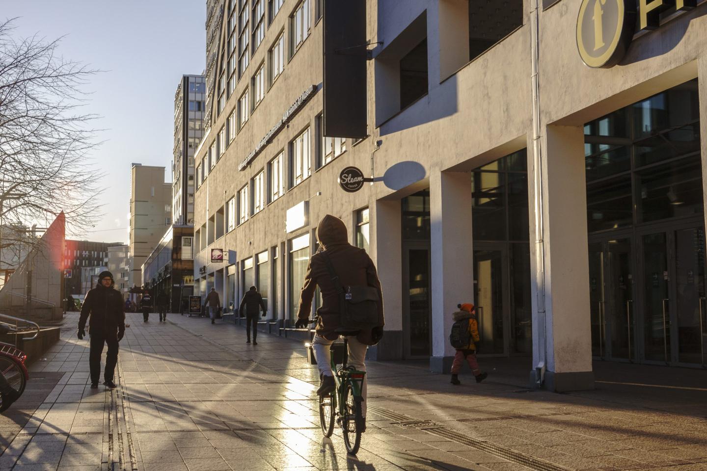A cyclist passes the Tennispalatsi recreation center in the Kamppi district of Helsinki, Finland.