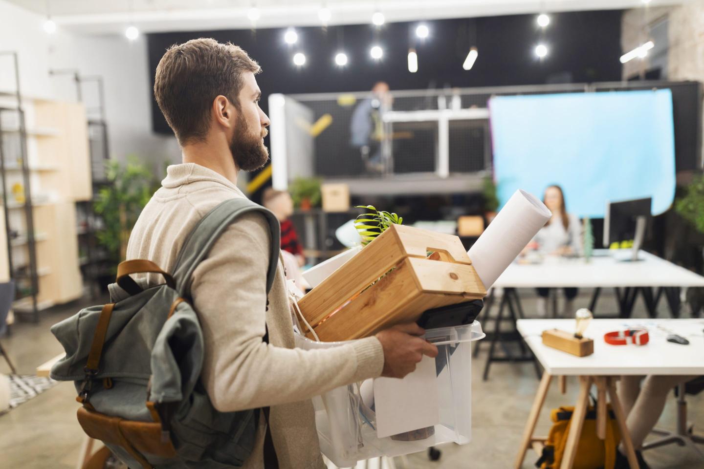 Young man carrying his belongings out of his workplace