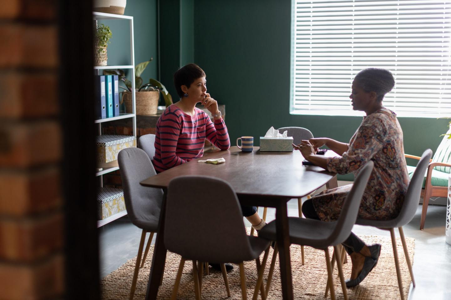Two women talking at counselling session in an office boardroom.