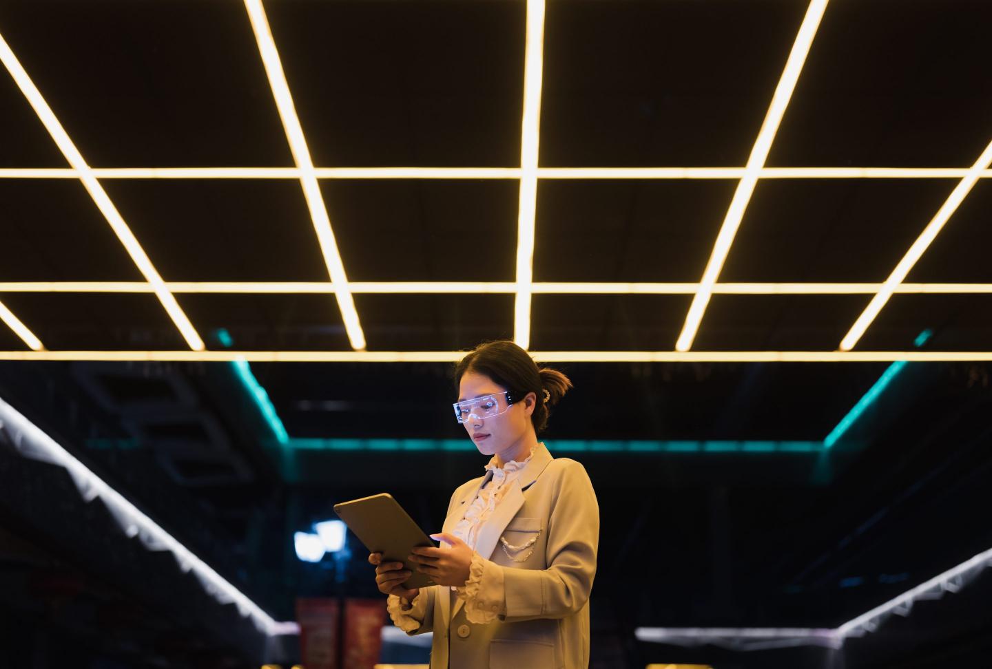 Young business woman wearing augmented reality glasses using tablet at night