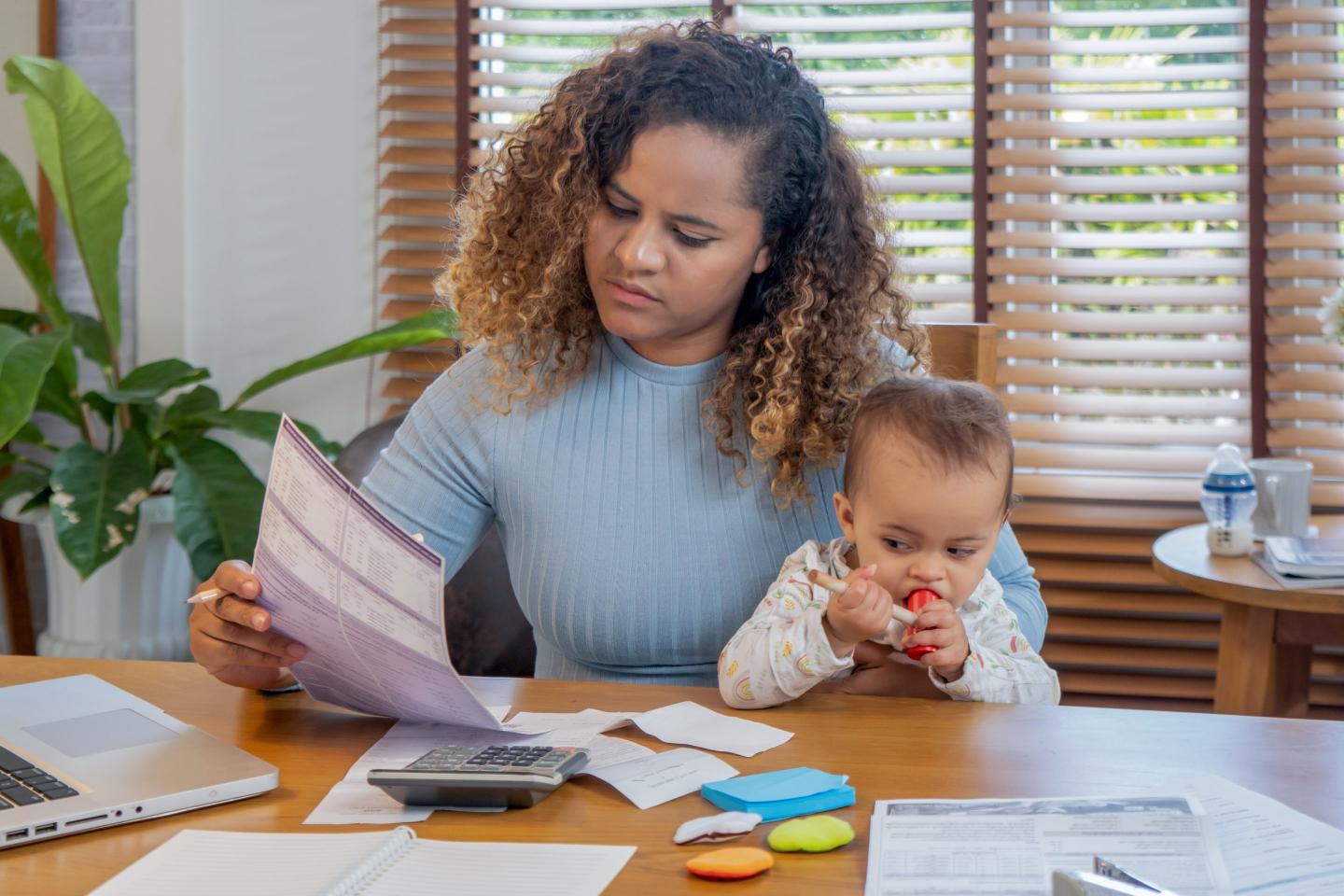 mother sitting at a table with baby and paperwork