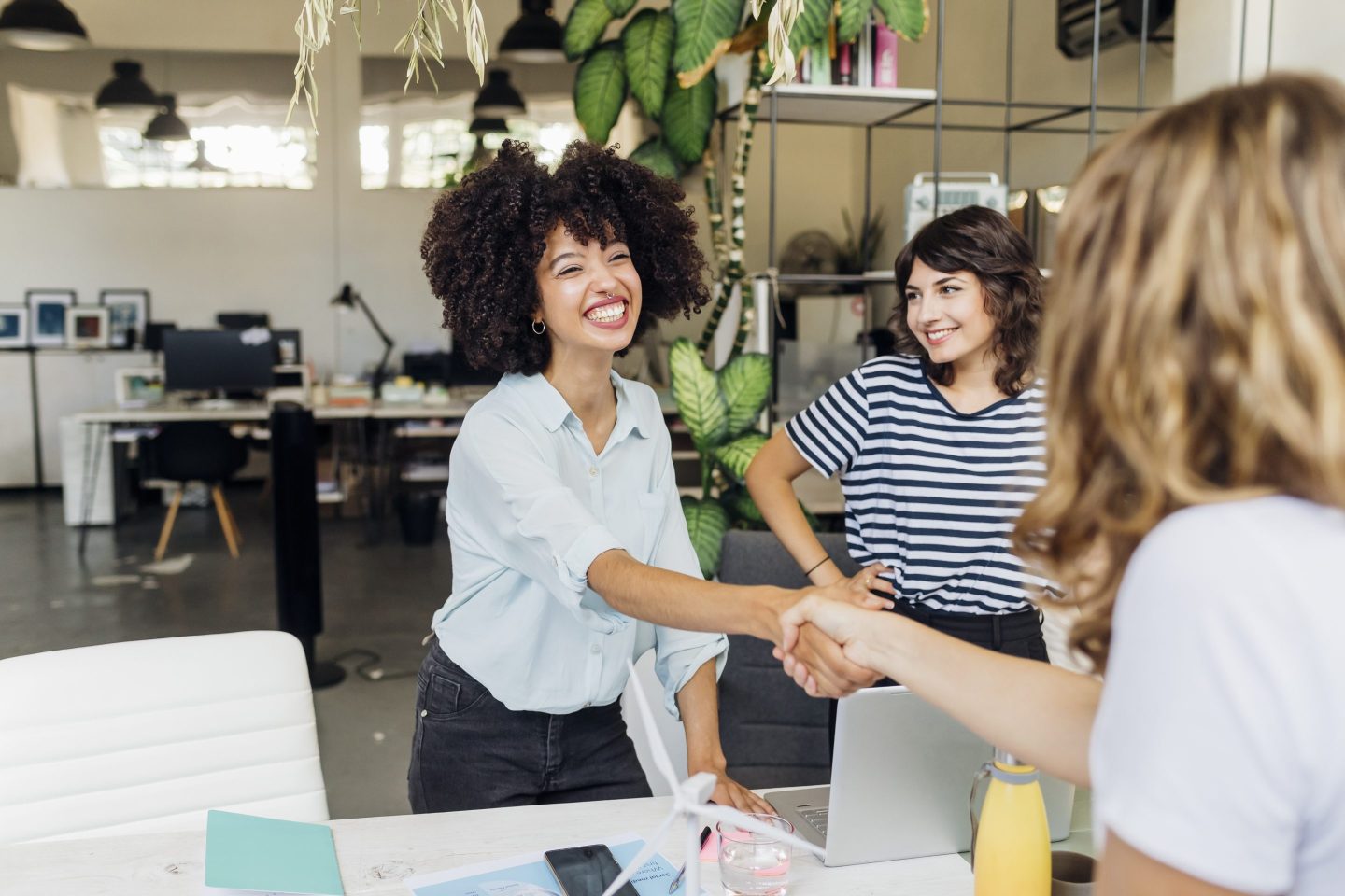 Happy businesswoman shaking hand with colleague at work place
