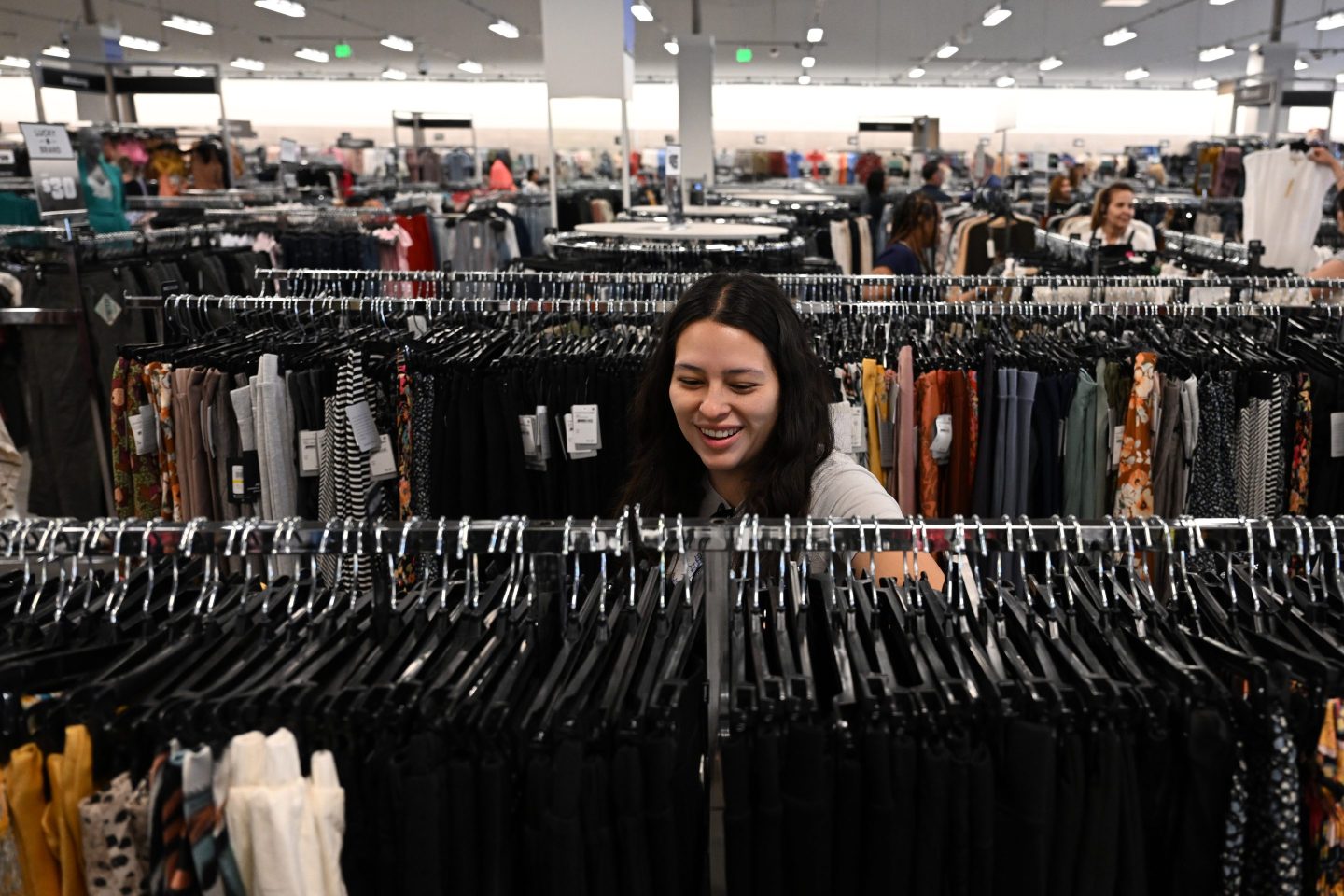 a female customer sorts through racks of clothing in a store