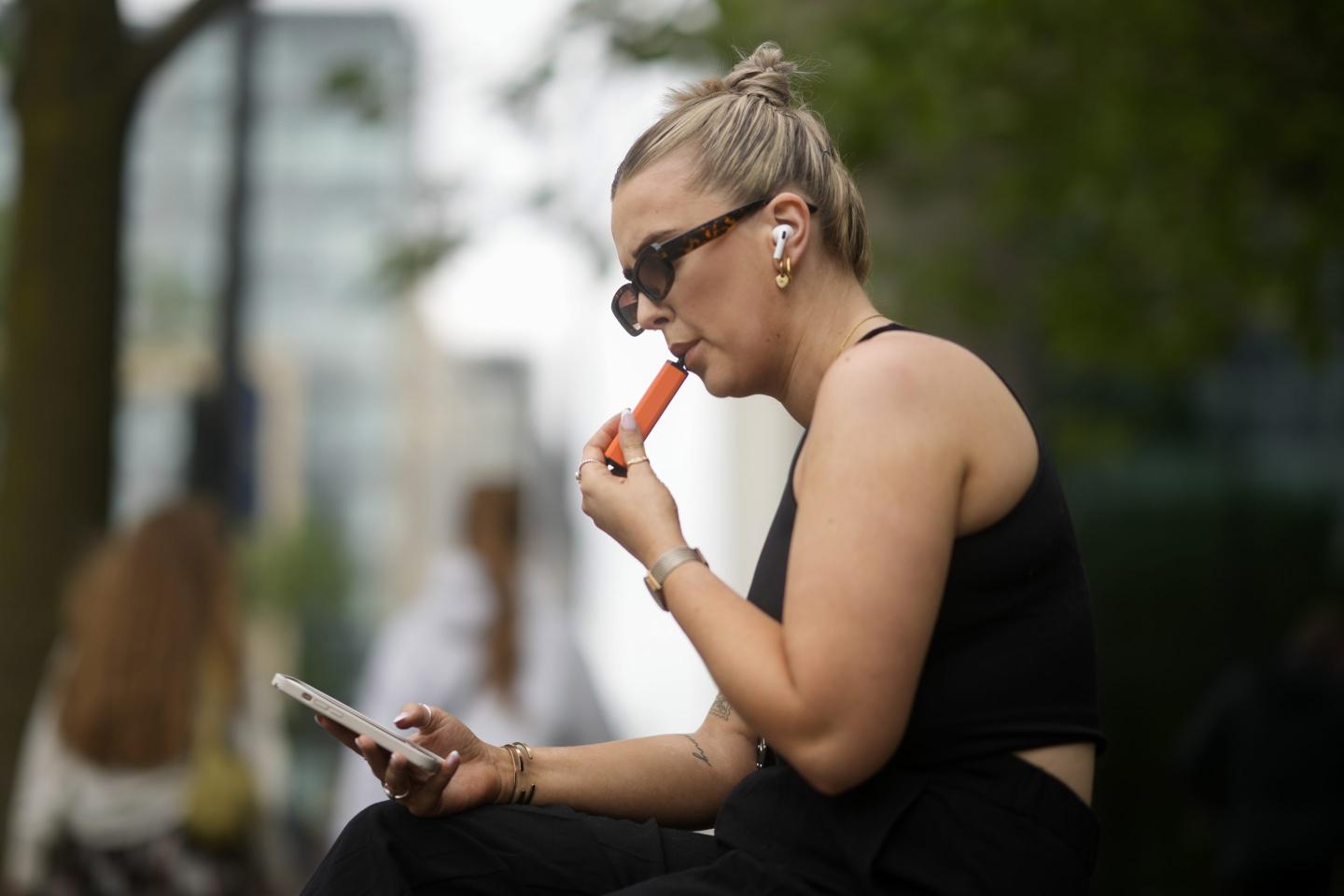 A woman smokes a vaping device on May 30, 2023 in Manchester, England.
